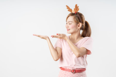 Asian woman is wearing christmas reindeer antlers over grey background.の写真素材