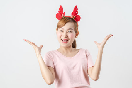Asian woman is wearing christmas reindeer antlers over grey background.の写真素材