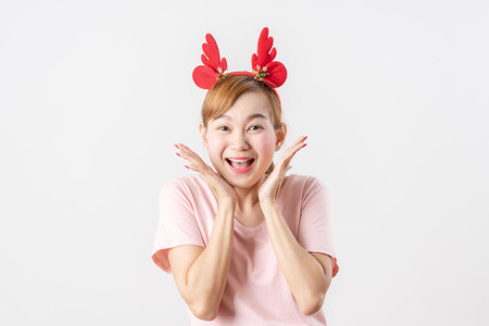 Asian woman is wearing christmas reindeer antlers over grey background.の写真素材
