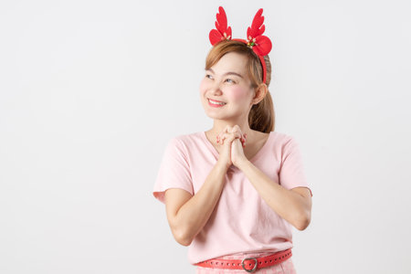 Asian woman is wearing christmas reindeer antlers over grey background.の写真素材
