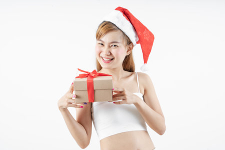 Asian woman is wearing christmas reindeer antlers holding big giftbox in hands grey background.の写真素材