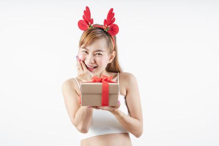 Asian woman is wearing christmas reindeer antlers holding big giftbox in hands grey background.の写真素材
