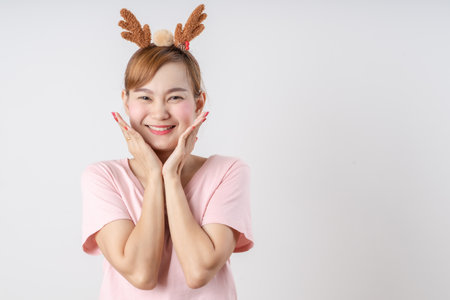 Asian woman is wearing christmas reindeer antlers over grey background.の写真素材