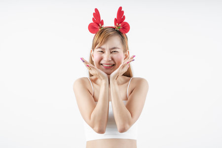 Asian woman is wearing christmas reindeer antlers over grey background.の写真素材