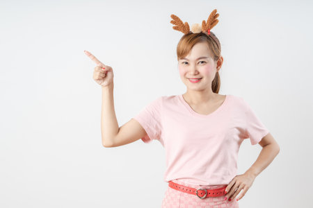 Asian woman is wearing christmas reindeer antlers over grey background.の写真素材
