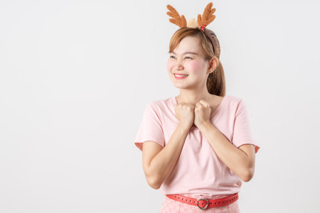 Asian woman is wearing christmas reindeer antlers over grey background.の写真素材