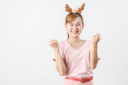 Asian woman is wearing christmas reindeer antlers over grey background.の写真素材