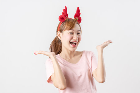 Asian woman is wearing christmas reindeer antlers over grey background.の写真素材