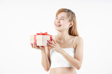 Asian woman is wearing christmas reindeer antlers holding big giftbox in hands grey background.の写真素材