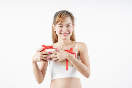 Asian woman is wearing christmas reindeer antlers holding big giftbox in hands grey background.の写真素材
