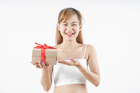 Asian woman is wearing christmas reindeer antlers holding big giftbox in hands grey background.の写真素材