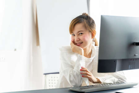 Portrait of smiling pretty young asian business woman on workplaceの写真素材