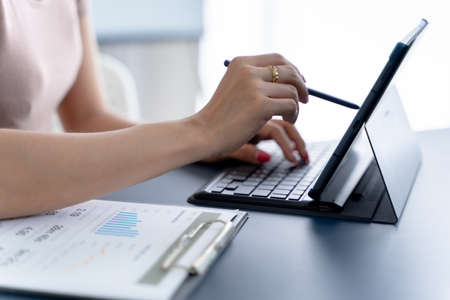 Business asian woman working with financial data hand using calculator and writing make note with...