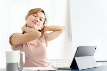 Young asian businesswoman feeling pain in neck after working on computer laptop for a long time. Office syndrome conceptの写真素材