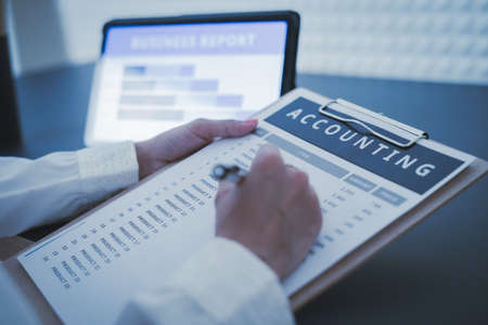 Business woman reviewing data in financial charts and graphs on wooden desk in office and business...