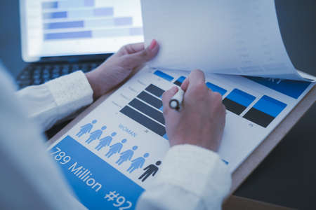 Business woman reviewing data in financial charts and graphs on wooden desk in office and business...