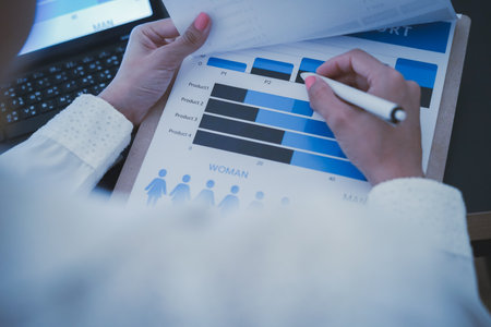Business woman reviewing data in financial charts and graphs on wooden desk in office and business working, tax, accounting, statistics and analytic research conceptの写真素材