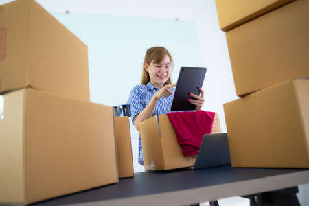 Entrepreneur owner receive and checking online purchase shopping order to preparing pack product box. Selling online ideas concept. Startup small businessの写真素材