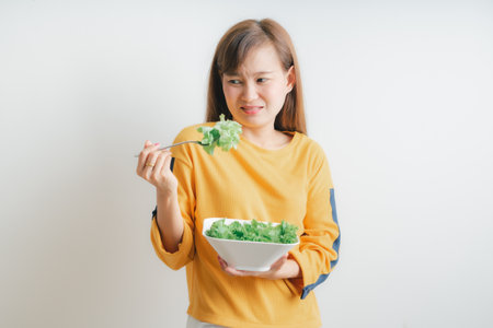 Asian woman eating a fresh salad isolated on whiteの写真素材