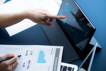 Asian business woman reviewing data in financial charts and graphs with tablet. Accountingの写真素材