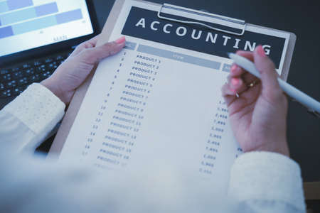 Business woman reviewing data in financial charts and graphs on wooden desk in office and business...