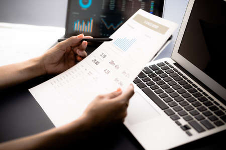 Asian business woman reviewing data in financial charts and graphs with tablet. Accountingの写真素材