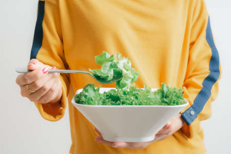 Asian woman eating a fresh salad isolated on whiteの写真素材