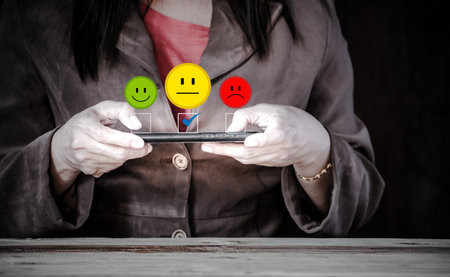Woman using mobile phone with smiley and sad emoji on the screen. customer service evaluation concept. give mediocre scores.の写真素材