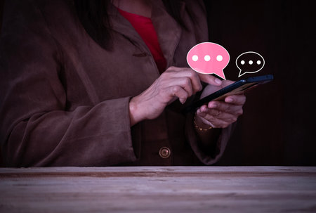 Women hand using smartphone typing Live chat chatting and social network concepts, chatting conversation working at home in chat box icons pop up. Social media marketing technology concept.の写真素材