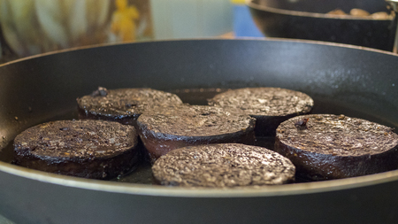 Breakfast of traditional sliced black pudding frying in a panの写真素材
