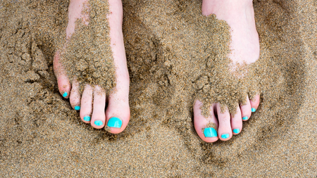 Toes against sand at the beach with painted nailsの写真素材