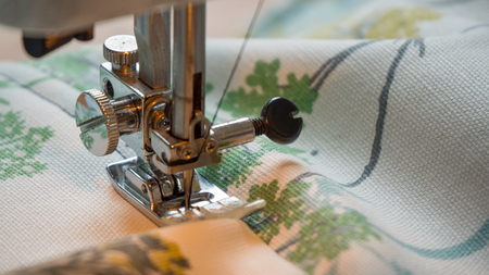 female hand using sewing machine stitching fabic