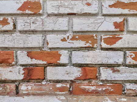 Old red brick wall painted white, scratched. Shattered color, corroded.