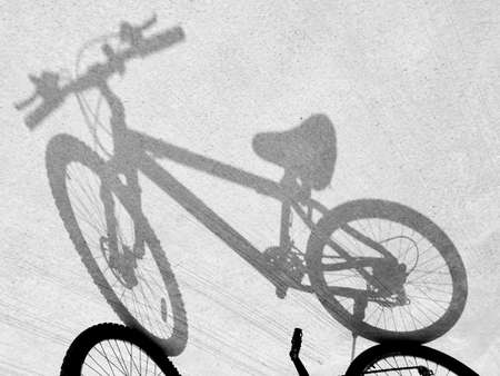 The light and shadow of the bicycle on the concrete road surface.の写真素材