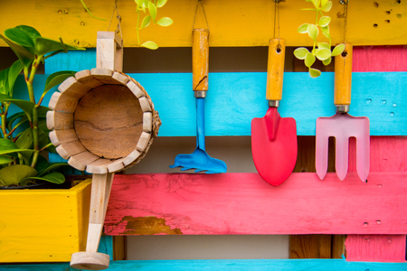 Garden tools and wooden bucket hanging on the colorful wood wall.の写真素材