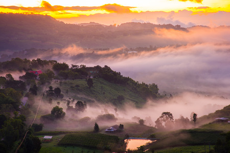 Dramatic vivid sunrise and fog with romantic cloudy sky and mountain background. Beauty of dawn sunbeam valley scene at Khao Takhian Ngo, Petchabun, Thailand.の写真素材
