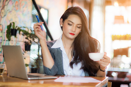 Young female freelancer working on marketing plan at coffee shop. Business concept.の写真素材