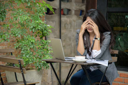 Tired businesswoman having a headache due to bankruptcy. Sleepy employee overworking making mistake. Business concept.の写真素材