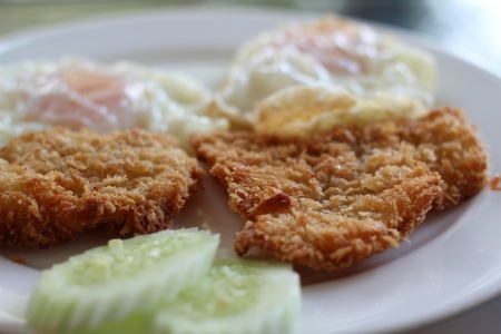 Fried fish served with eggs and cucumberの写真素材