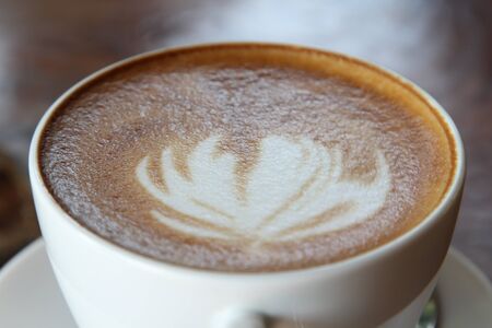 Hot cappuccino in white cup on wooden table.の写真素材