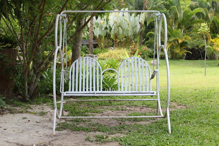 White garden swing seat alone in the garden.の写真素材
