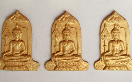 Row of Buddha statues on Buddhist temple wall.の写真素材