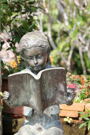 Bronze statue of a girl reading a book in the garden.の写真素材