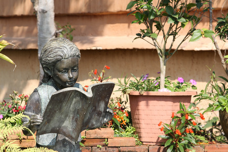 Bronze statue of a girl reading a book in the garden.の写真素材