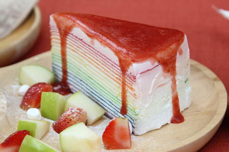 Rainbow crape cake and fruit on wooden plate.の写真素材