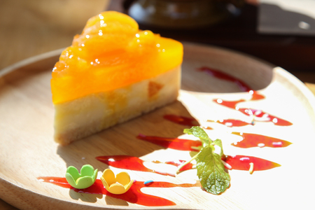 Orange cake on wooden plate, focus on small flower.の写真素材