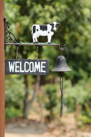 Black metal WELCOME sign on brown pole.の写真素材