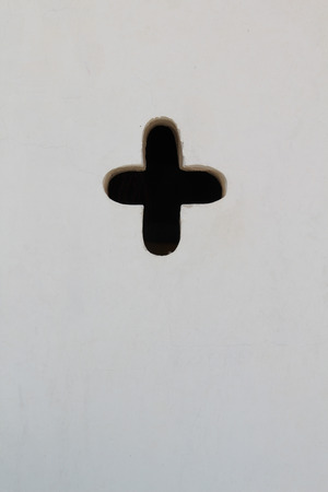 White concrete wall with hole plus sign.の写真素材