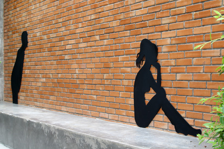 Black wooden couple figure on brick wall.の写真素材