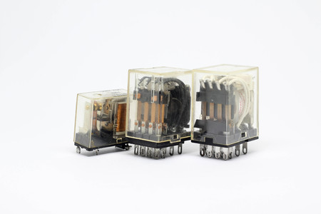 Three electrical auxiliary relays in transparent plastic cases on white background.のeditorial素材